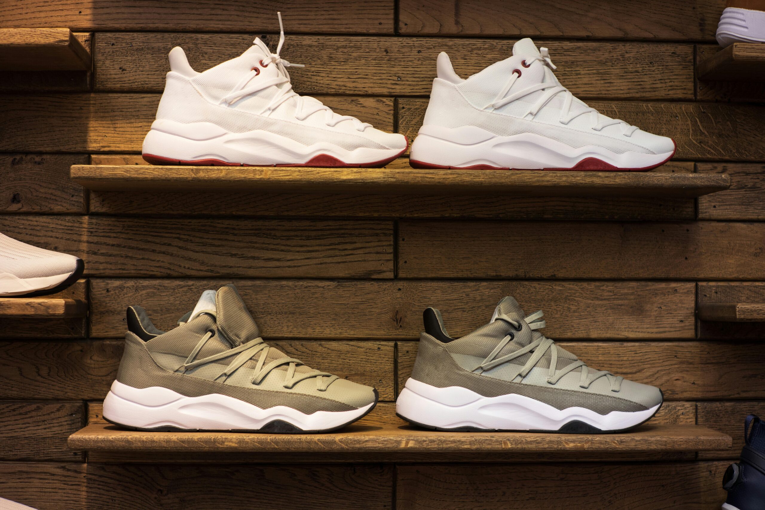 Modern athletic sneakers displayed on wooden shelves in a footwear store
