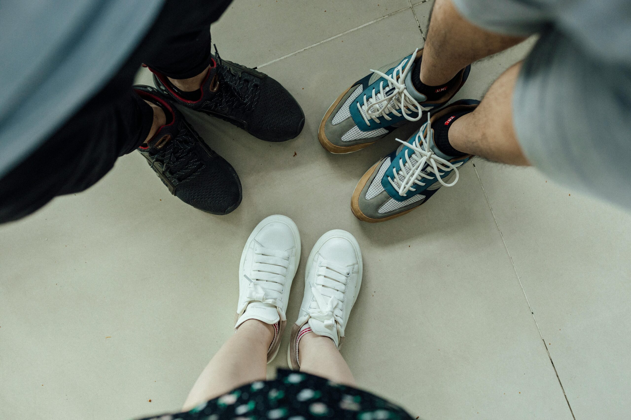 Top view of people standing in different casual sneakers on a light floor